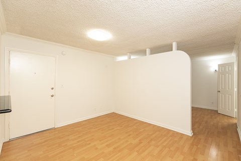 an empty living room with a wood floor and white walls