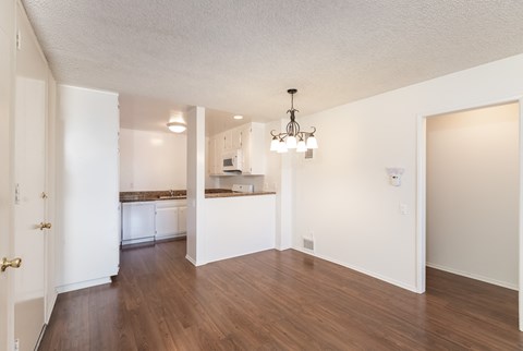 an empty living room and kitchen with white walls and wood floors