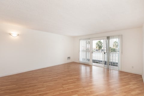 an empty living room with wood flooring and a balcony