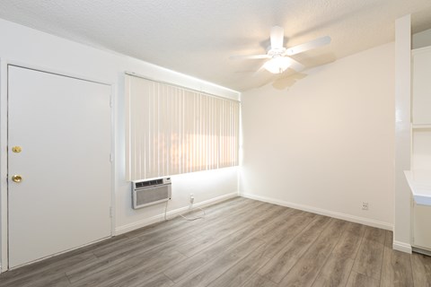 an empty living room with a ceiling fan and a window