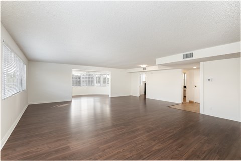 the living room and dining room of an empty apartment
