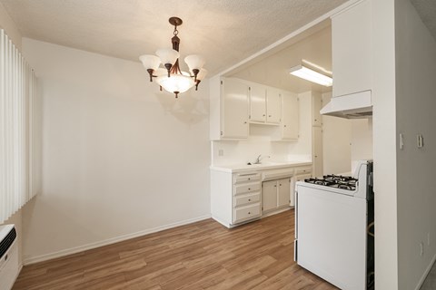 an empty kitchen with white cabinets and a white stove top oven