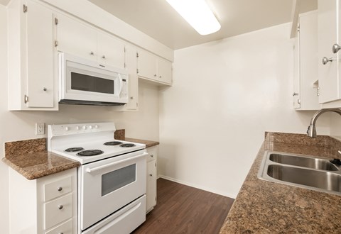 a kitchen with white appliances and granite counter tops and white cabinets