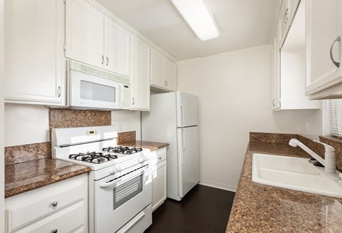 a kitchen with white appliances and granite counter tops and white cabinets