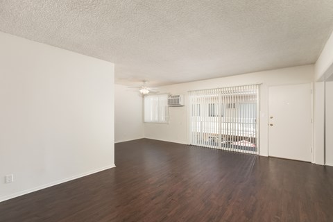the living room of an apartment with a wood floor and white walls