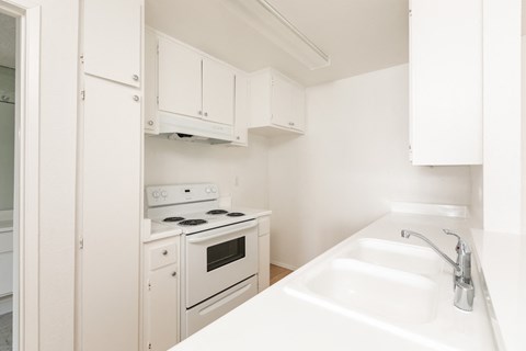 a kitchen with white appliances and white cabinets and a sink