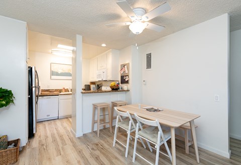 a dining room and kitchen with a table and chairs and a ceiling fan
