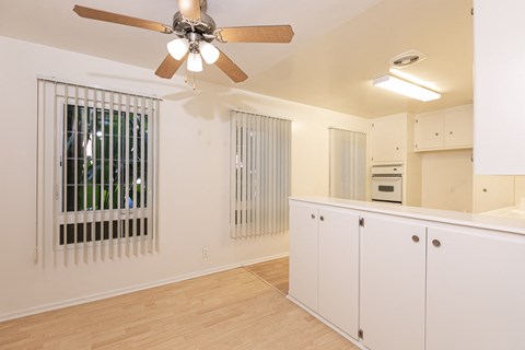 the living room and kitchen of an apartment with a ceiling fan