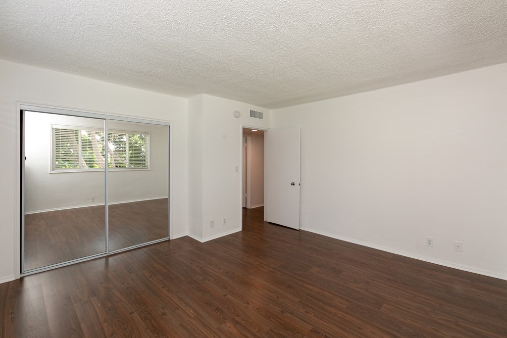 Bedroom with Hardwood Floors and Mirrored Wardrobe Closet