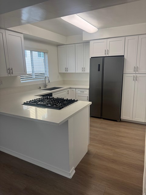A kitchen with white cabinets and a black fridge.