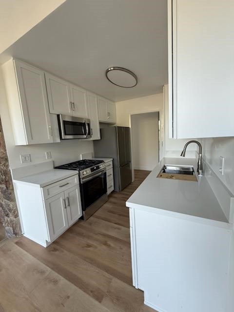 A kitchen with white cabinets and a wooden floor.