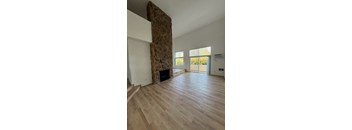 Living room with stone fireplace and wood flooring