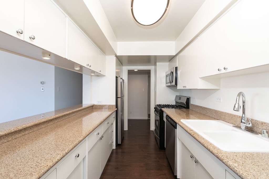 A kitchen with white cabinets and a beige countertop.