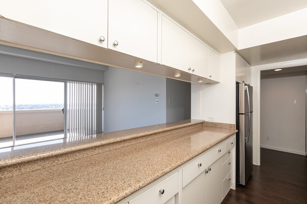 A kitchen with white cabinets and a granite countertop.