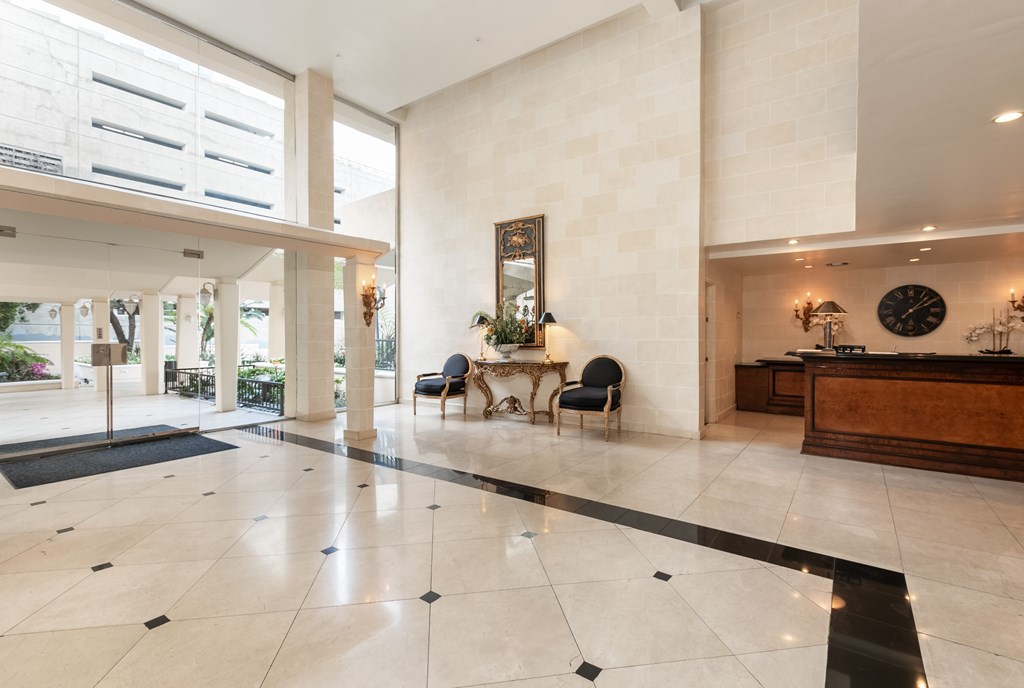 A spacious lobby with marble floors and a reception desk.