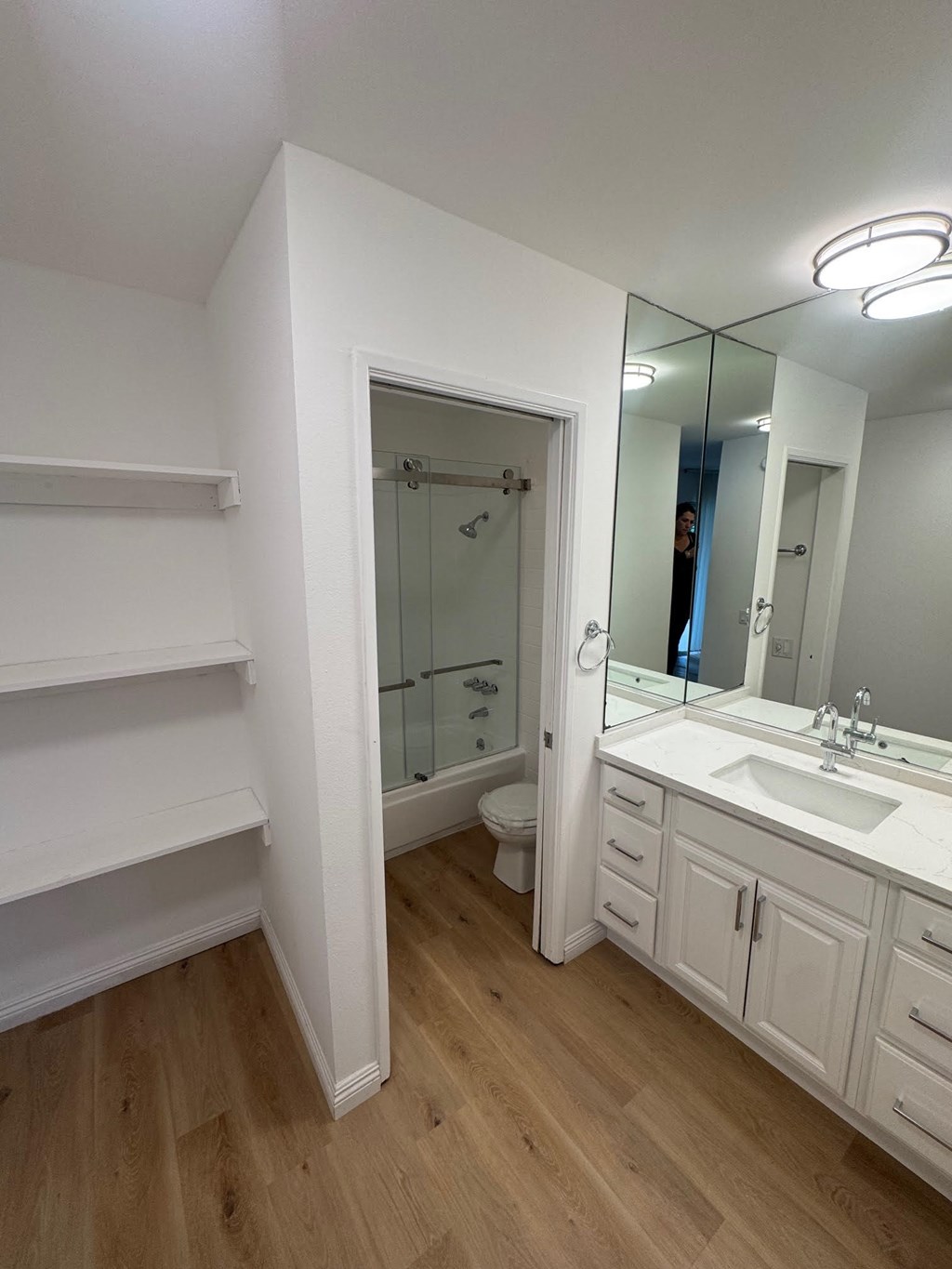 A white bathroom with a sink, mirror, and a walk-in shower.