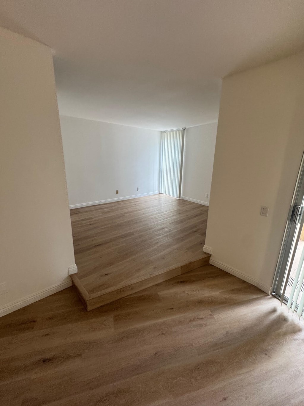 A room with wooden flooring and white walls.