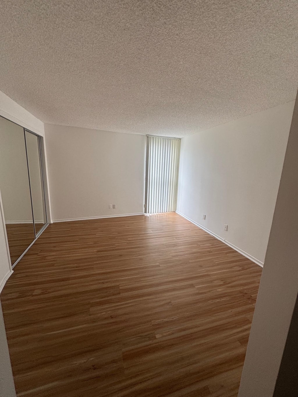 Bedroom with wooden flooring and a sliding glass door.
