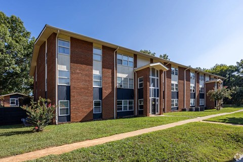 A red brick building with a yellow roof and a green lawn in front.