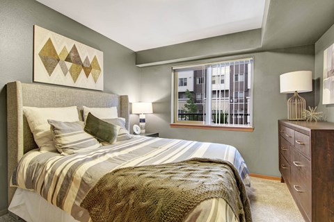 A bedroom with a large bed and a window with a view of a building outside.