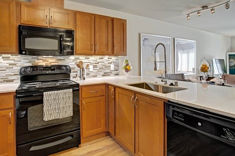 A kitchen with wooden cabinets and black appliances.