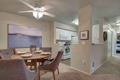 Open dining area beside a bright kitchen with white cabinetry.