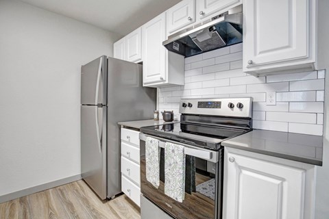 A modern kitchen with a stainless steel refrigerator and a stove top oven.