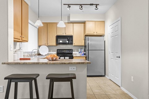 a kitchen with wooden cabinets and a counter top with three stools