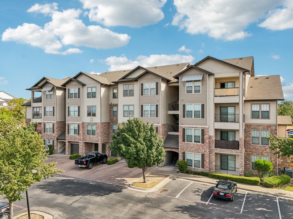 A large apartment complex with a parking lot in front.