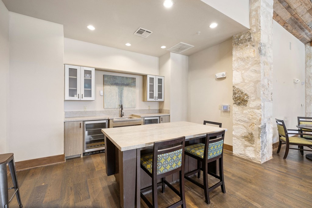 a kitchen with a large island with four chairs in front of it at Lakeline East Apartments, Cedar Park, TX