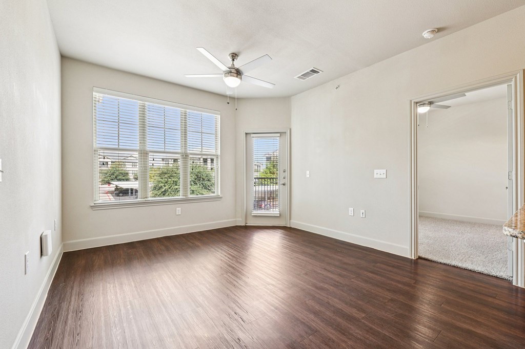 A room with a ceiling fan and a view of the outside through the window.