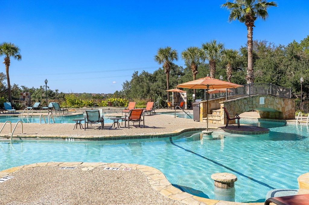 a swimming pool with chairs and umbrellas and palm trees at The Verandah, Austin