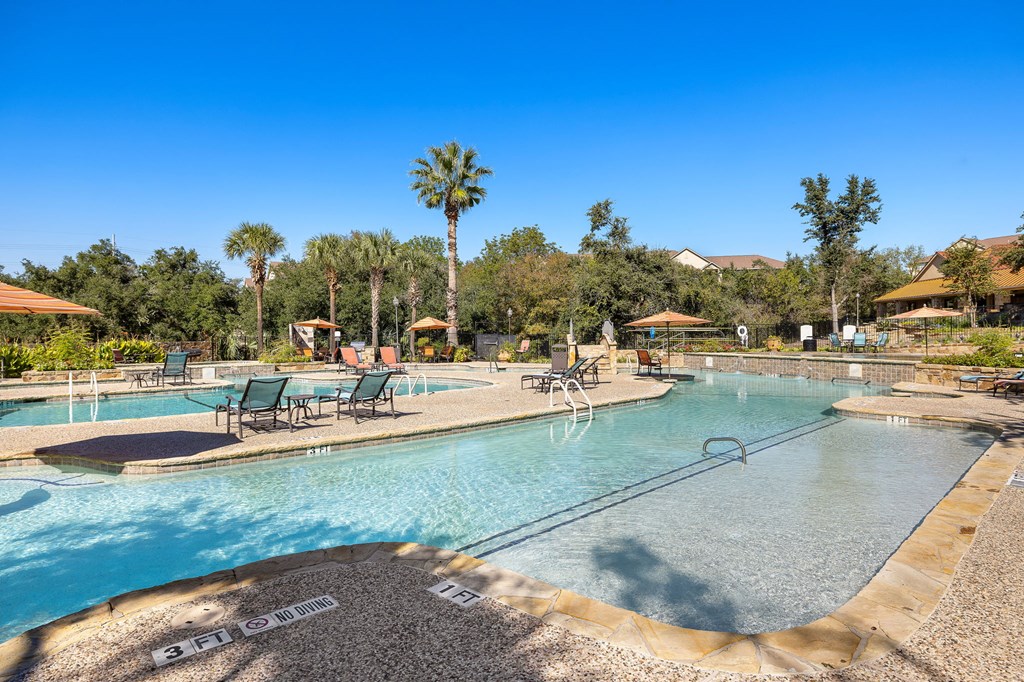 a swimming pool with chairs and trees in the background at The Verandah, Austin, TX