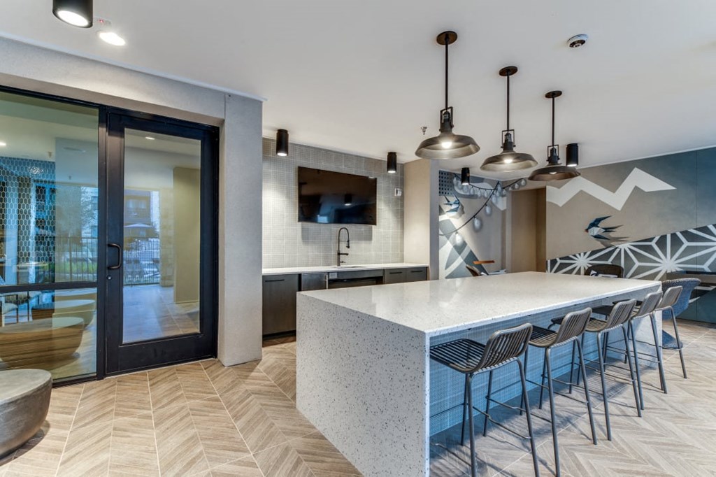a kitchen with a large white counter top and a long white island with a bunch of chairs at Aurora Watson Branch, Texas