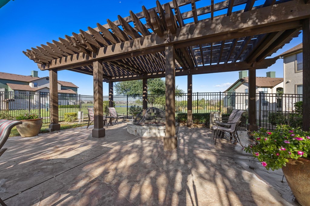 a patio with a wooden pergola and a fire pit at The Fairways at Star Ranch, Texas