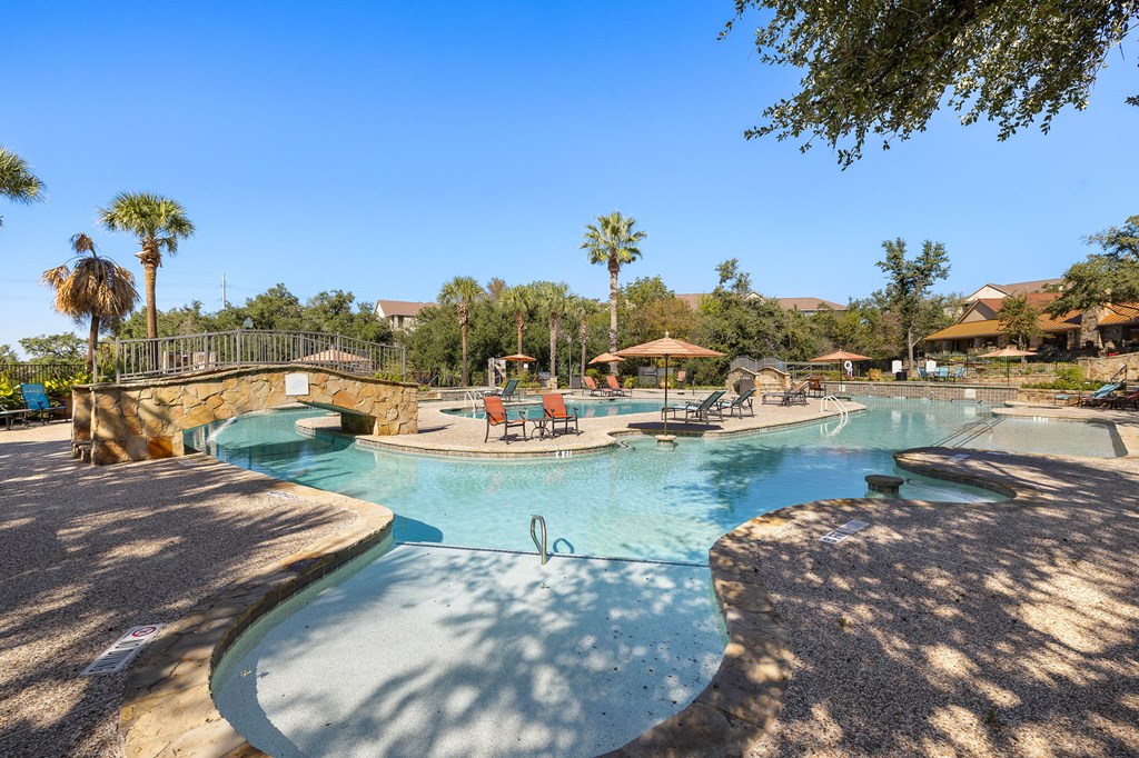 a resort style swimming pool with a bridge and trees at The Verandah, Austin