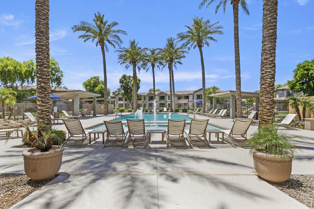 a swimming pool with chaise lounge chairs and palm trees at Adiamo Palm Valley, Goodyear, AZ
