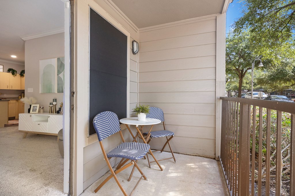 a small table and two chairs sit on a balcony in front of a kitchen at Artisan Apartments & Shops, Texas, 78729