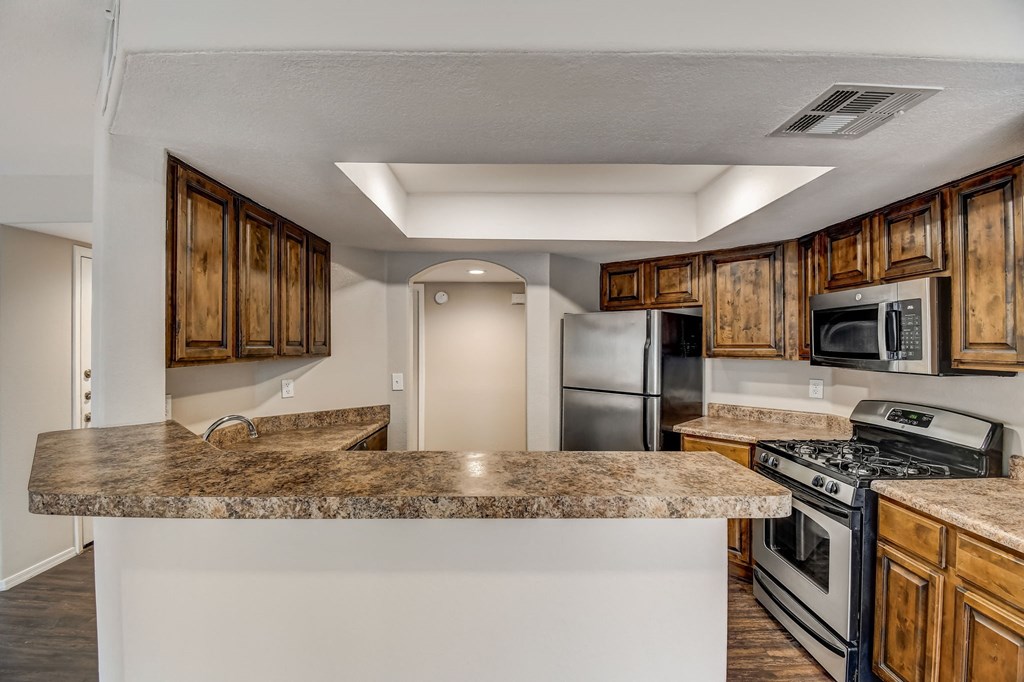 a kitchen with a granite counter top and a stove and refrigerator  at San Montego Apartments, Mesa, AZ