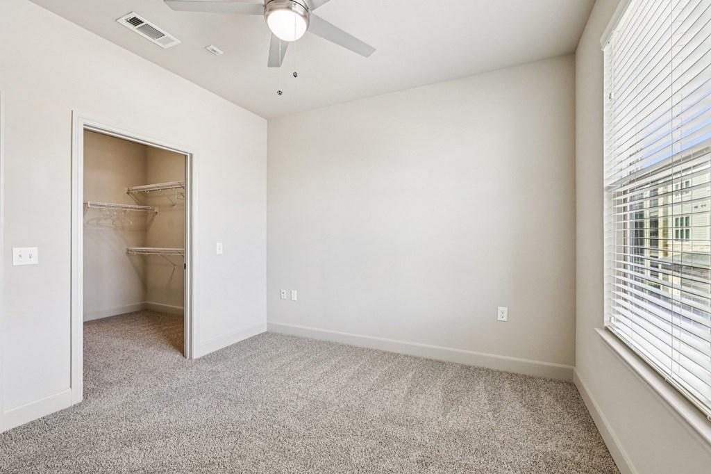 A room with a ceiling fan and a doorway leading to another room.