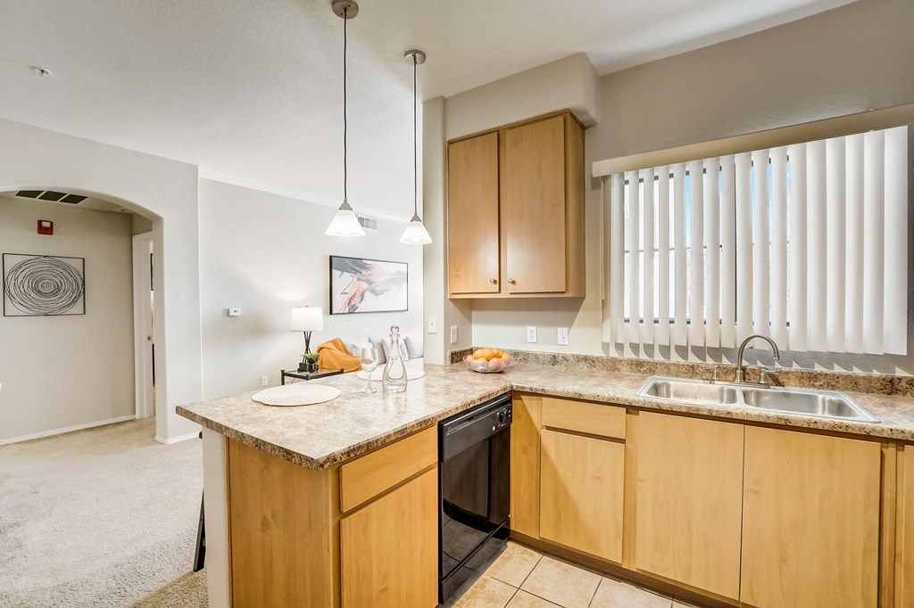 a kitchen with wooden cabinets and a counter top with a sink  at Adiamo Palm Valley, Goodyear, 85395