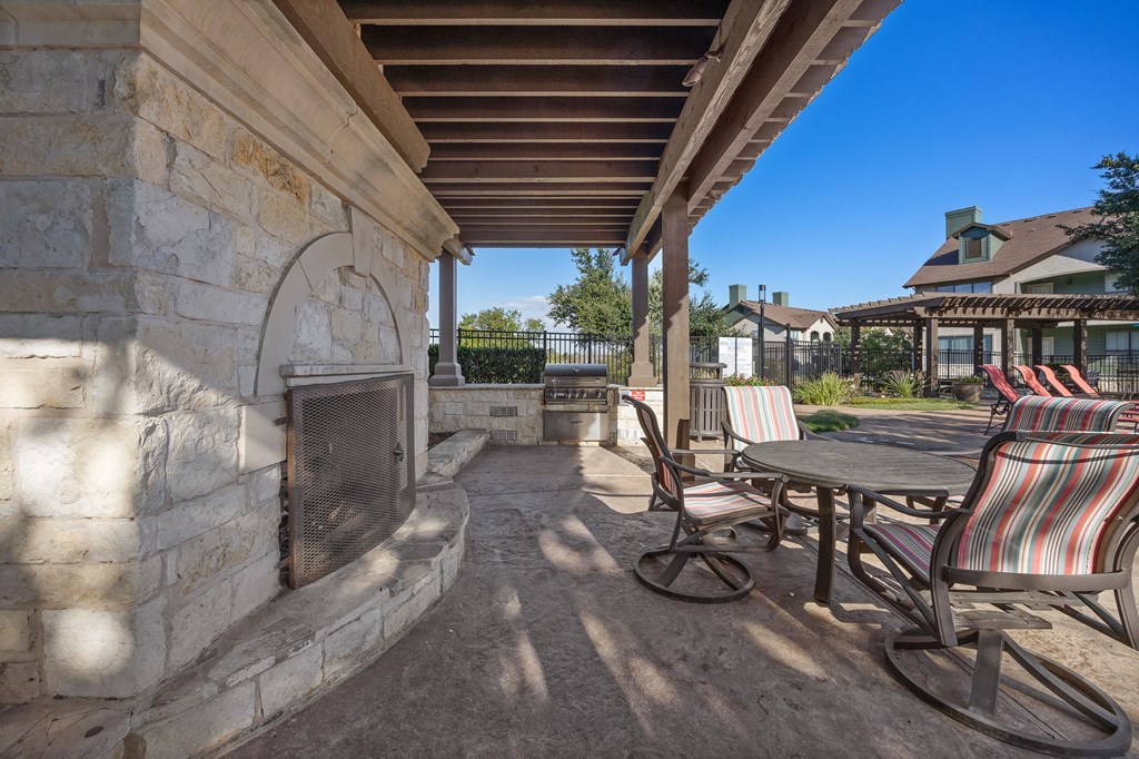 a covered patio with chairs and a table and a fireplace at The Fairways at Star Ranch, Hutto