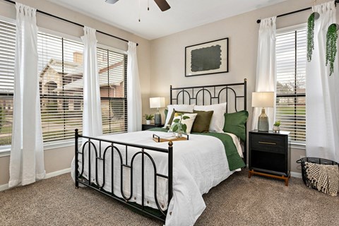 Bedroom with black metal bed frame and green accents at The Fairways at Star Ranch Apartments, Hutto