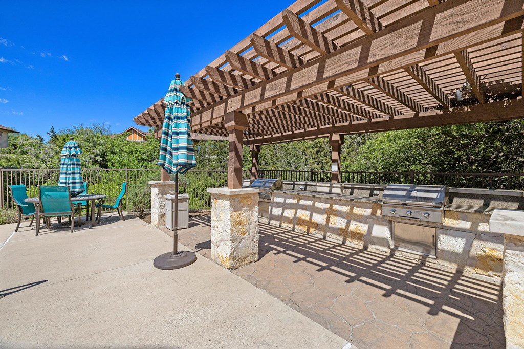 a patio with a pergola and table with umbrellas at Lakeline East Apartments, Cedar Park