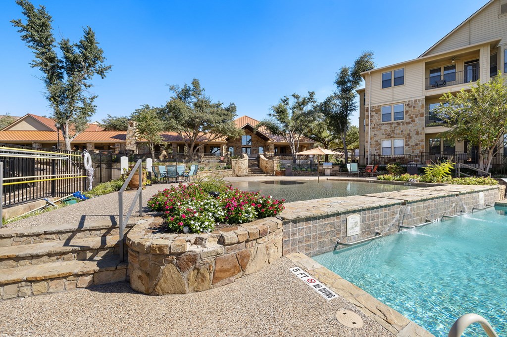 a resort style swimming pool with a stone retaining wall and a building with a pool at The Verandah, Austin, 78726