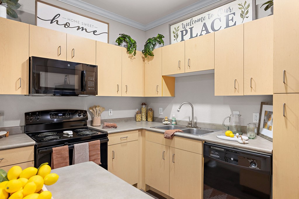a kitchen with wooden cabinets and black appliances at Artisan Apartments & Shops, Austin, Texas