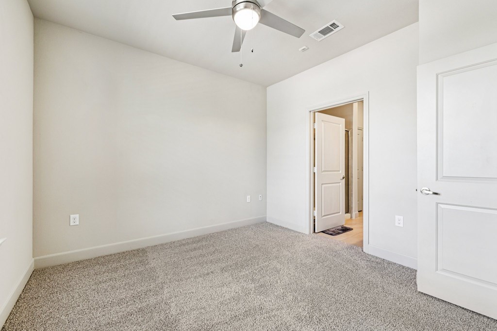 A room with a ceiling fan and carpeted floor.