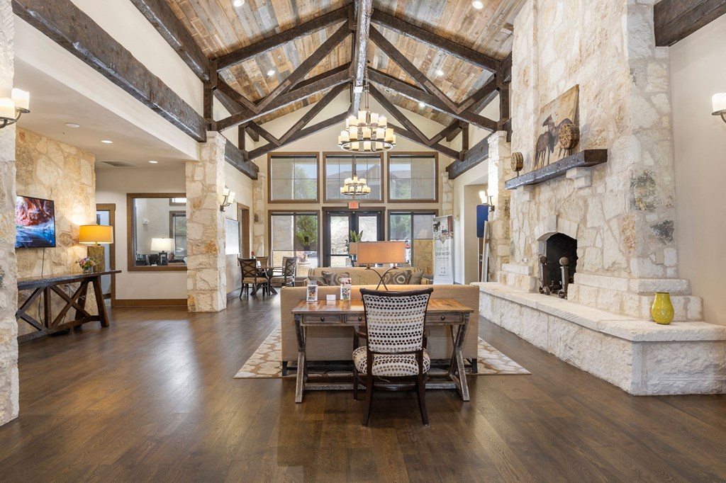 a dining room with a table and chairs in front of a stone fireplace at Lakeline East Apartments, Cedar Park