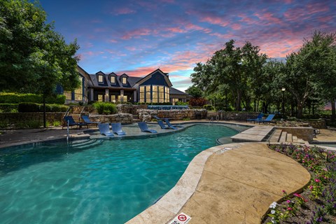 a swimming pool with a house in the background at sunset