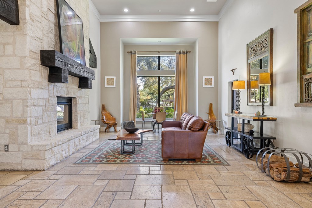 the living room has a stone fireplace and a leather couch at Sonterra Apartment Homes, Austin, 78726